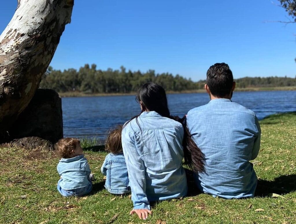 family sitting under the tree by water