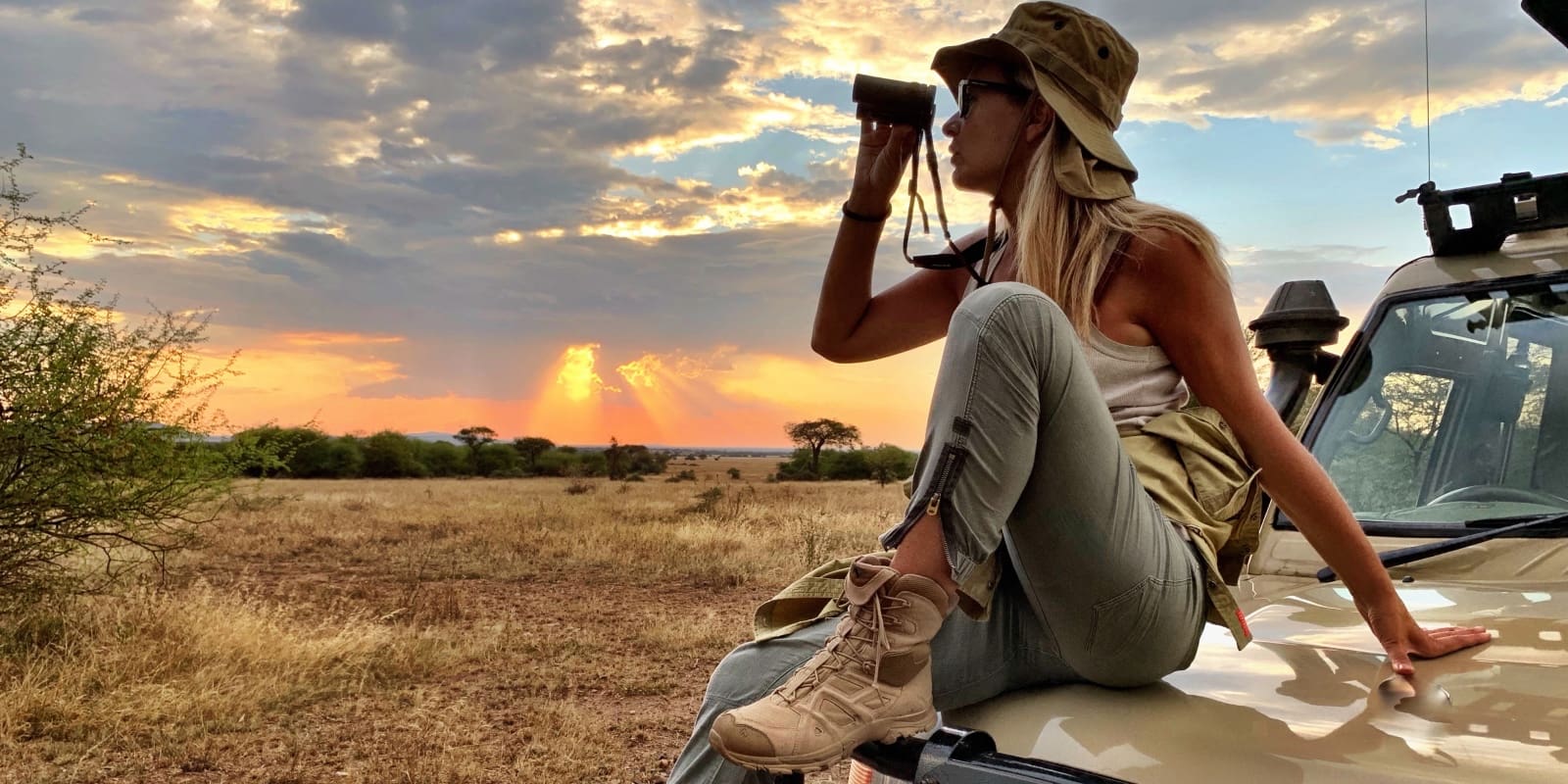 Woman On Vehicle Field Against Sky During Sunset