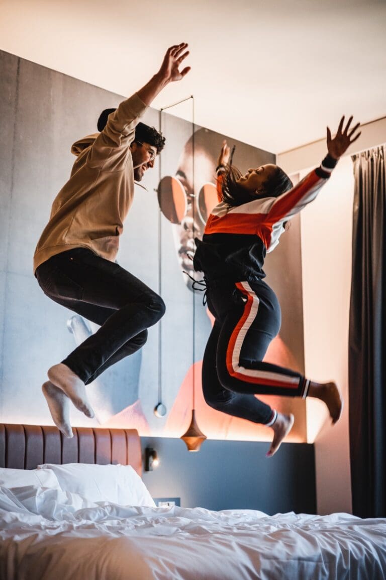 a couple jumping on a hotel bed