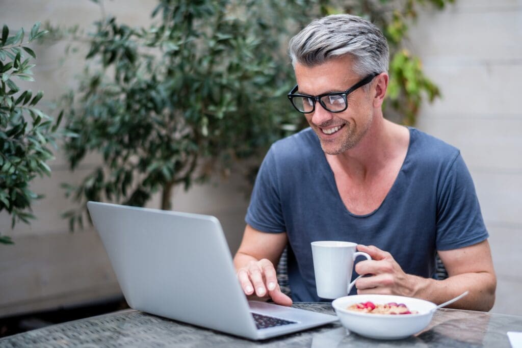 White male sitting and having breakfast in front of his mac