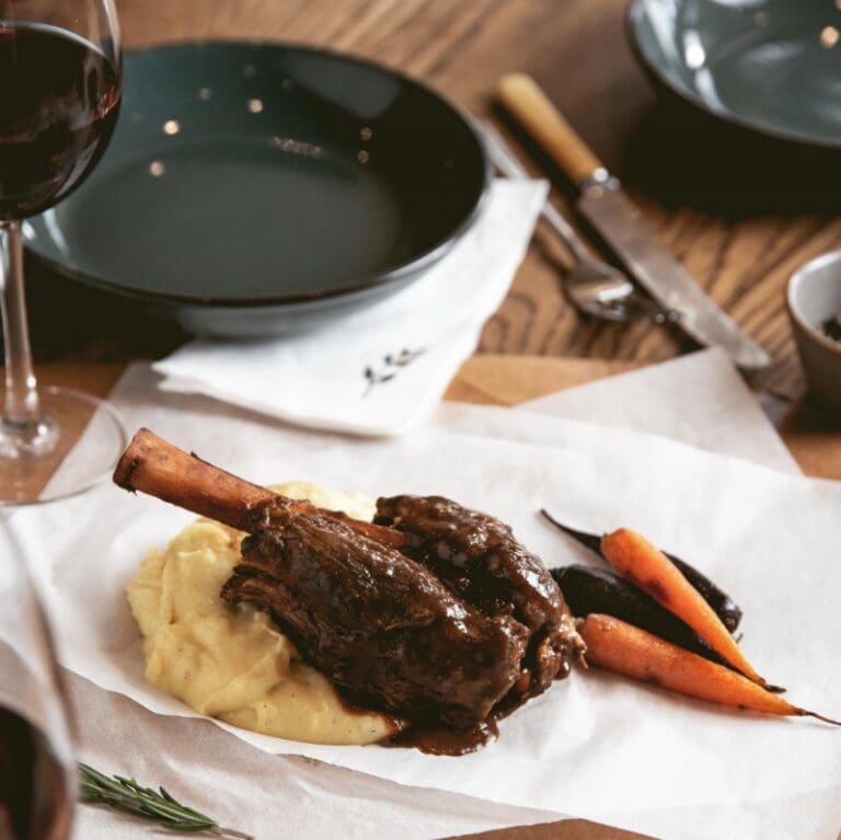 Lamb shank on a restaurant table with wine