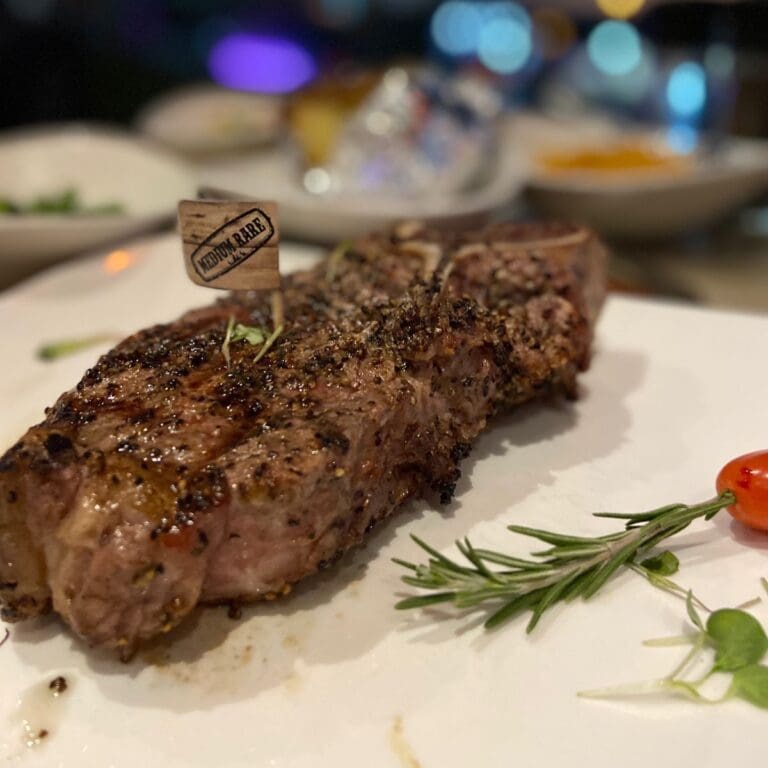 Medium rare t-bone steak on a white plate