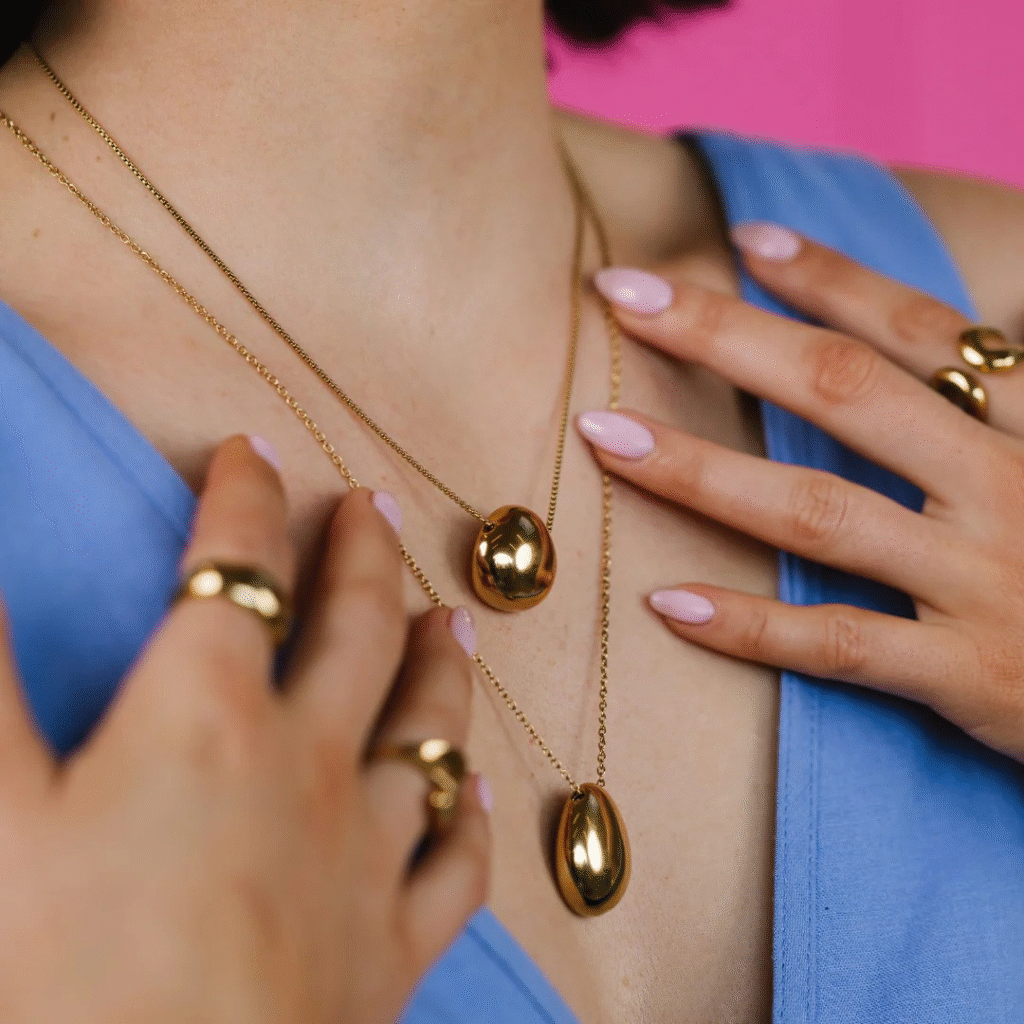 Women wearing gold plated jewellery including rings and necklaces.