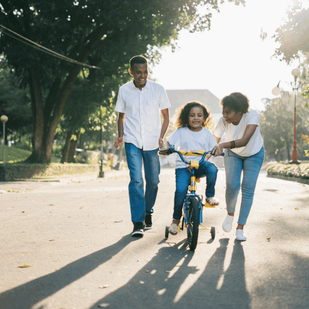 family teaching child how to ride a bicycle