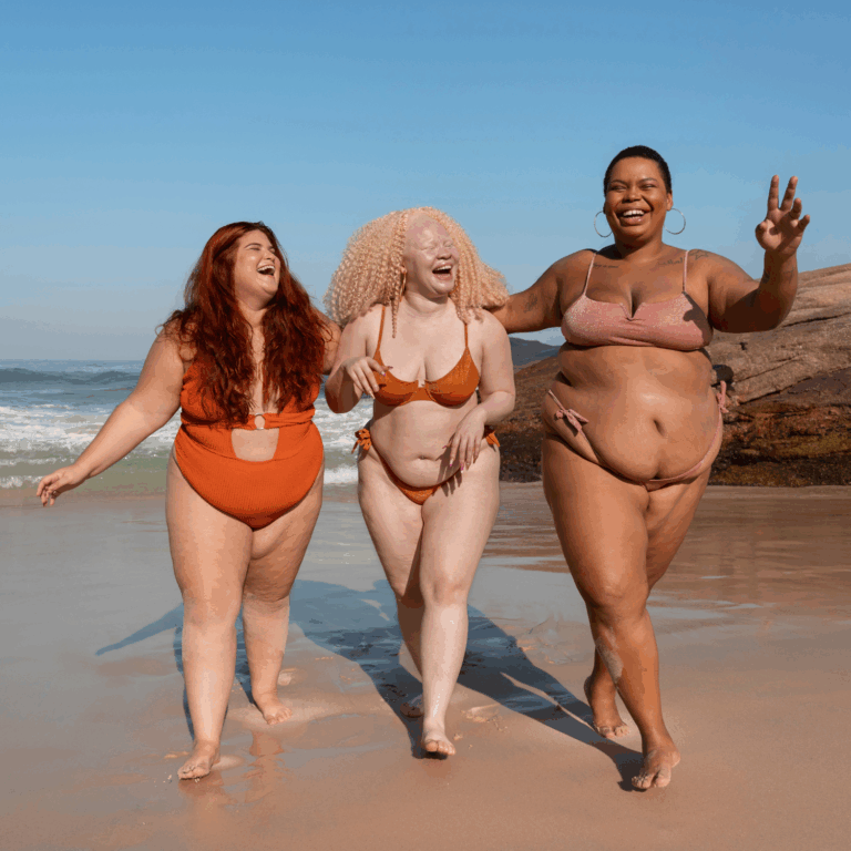 Three overweight ladies walking on a beach in bikinis