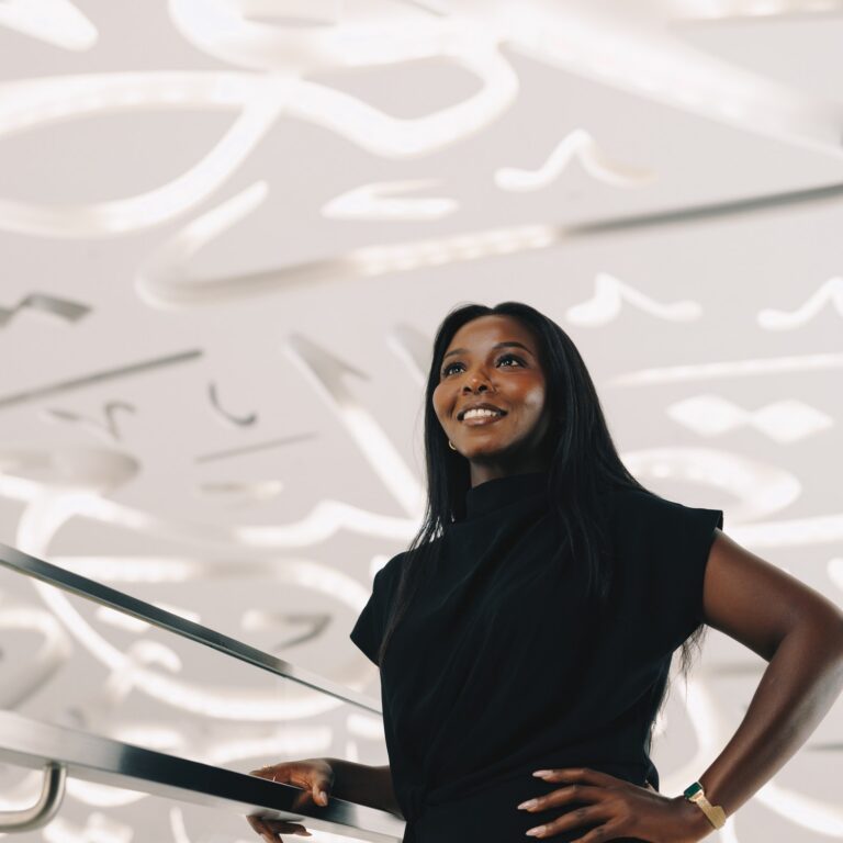 Elizabeth Wambui standing beside a reflective architectural surface