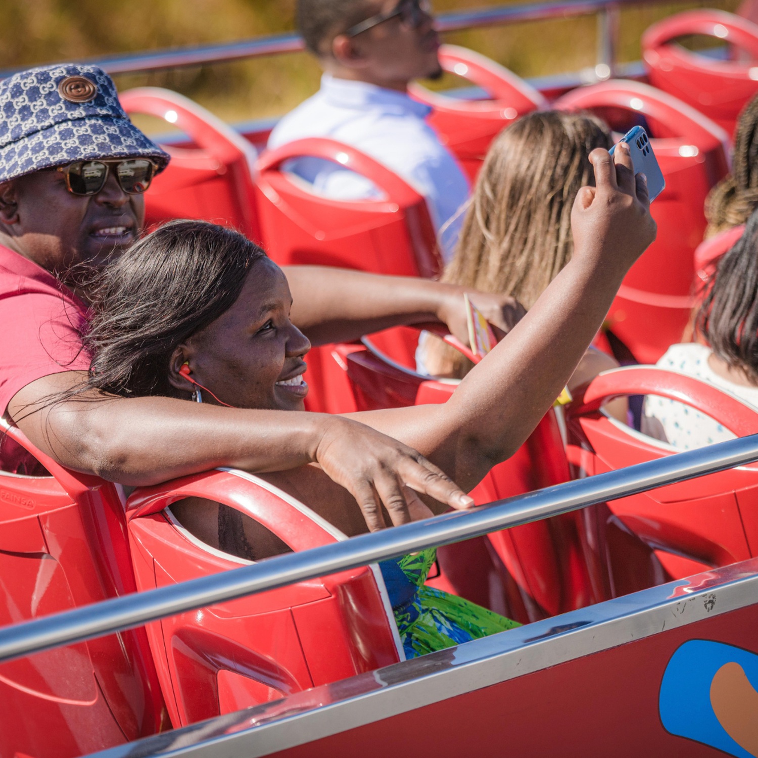Passengers taking photographs from the open upper deck of a City Sightseeing bus